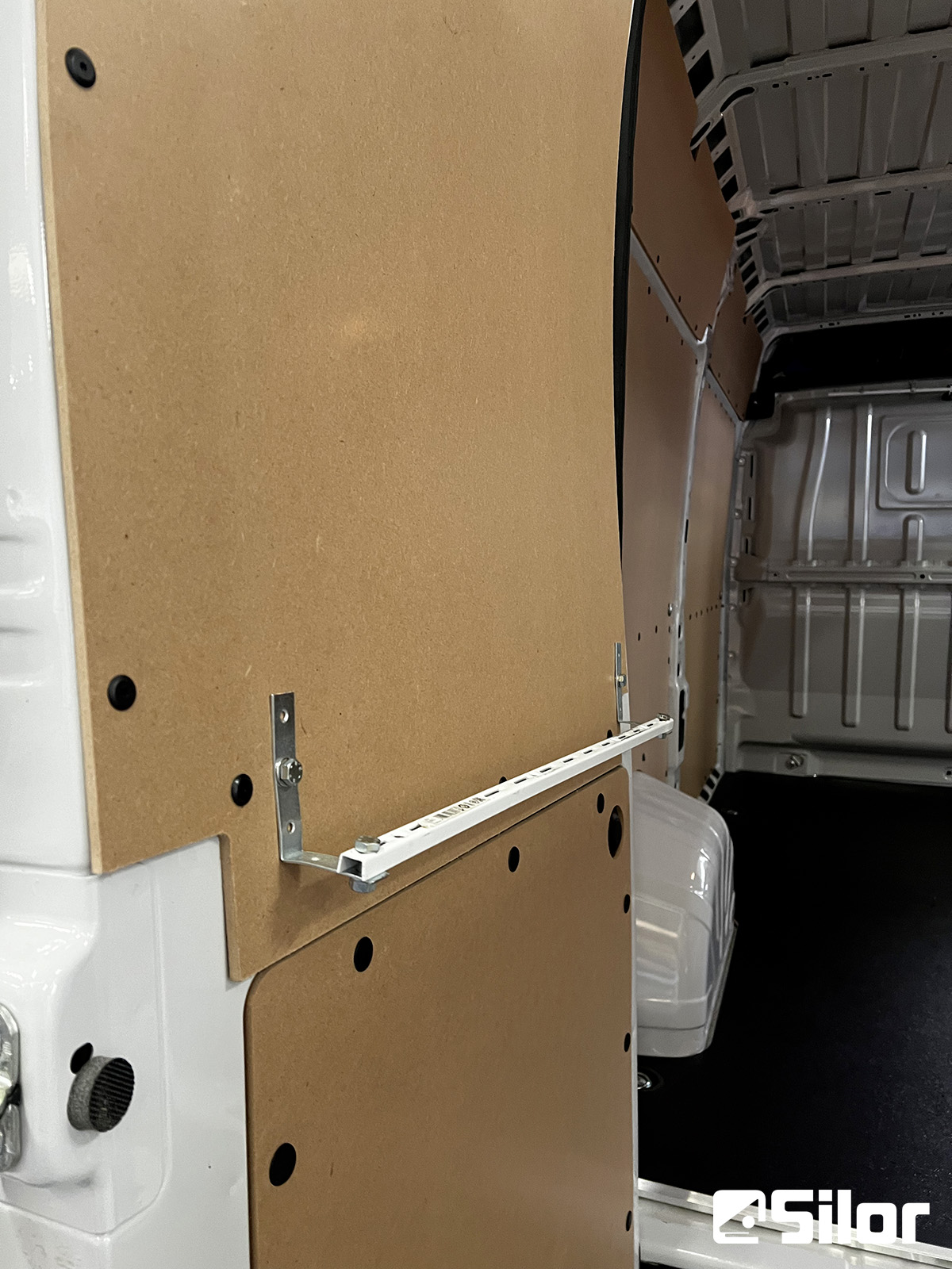 Interno di un furgone con rivestimento in legno e binari.