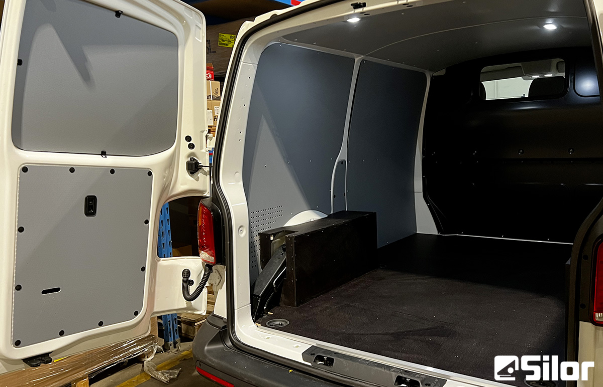 Interno di un furgone bianco con pannelli grigi e neri.