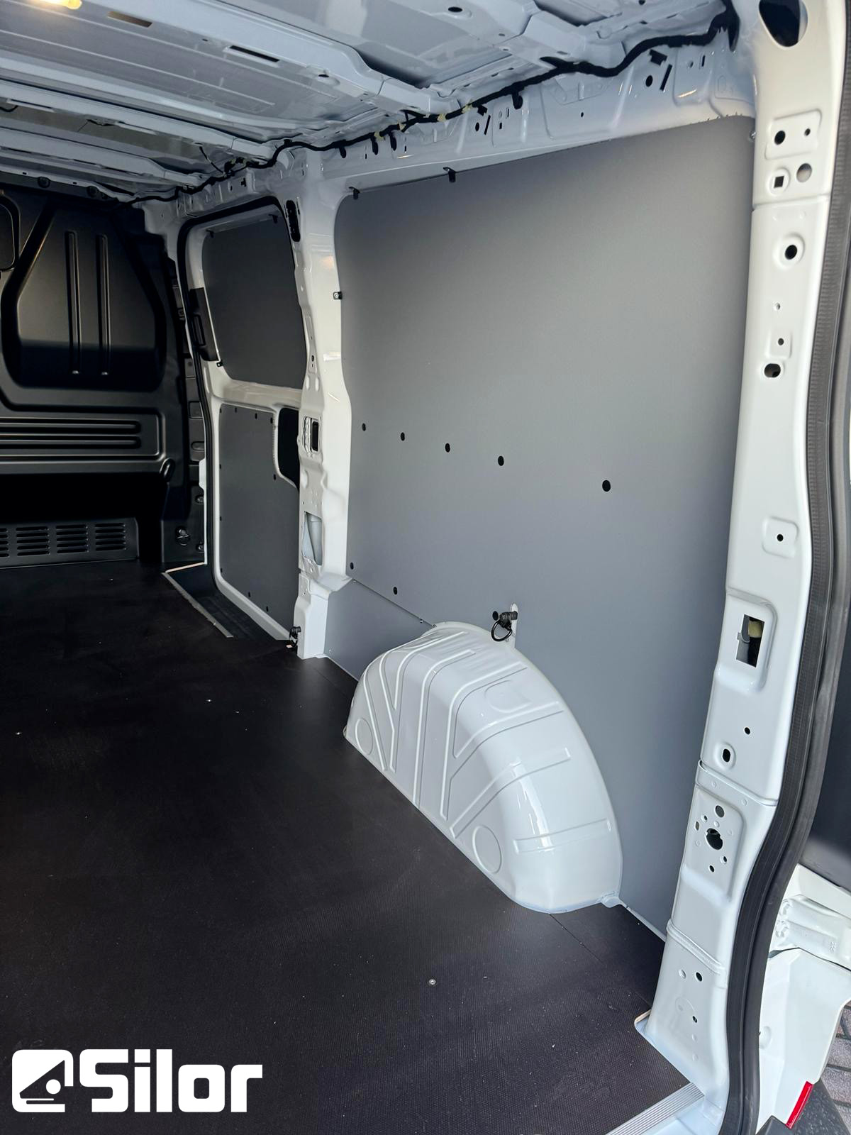 Interni di un furgone commerciale con pannelli grigi e pianale in gomma nera.