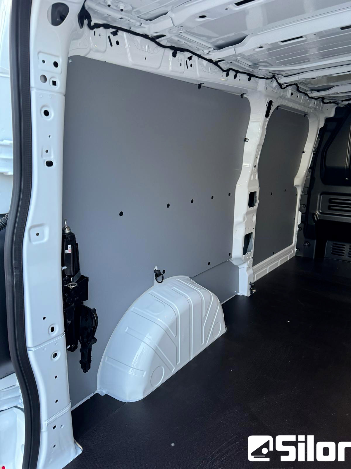 Interni di un furgone bianco, con pavimento nero e pannelli grigi.