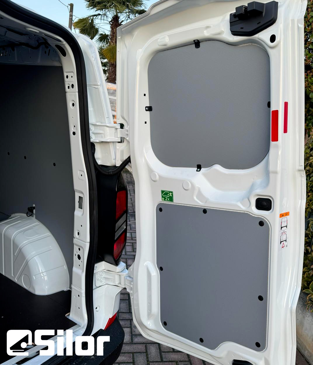 Interno di un furgone bianco con le portiere posteriori aperte.