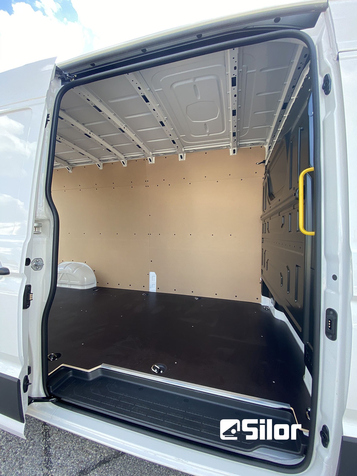 Interni di un furgone bianco con rivestimento in legno e pavimento nero.