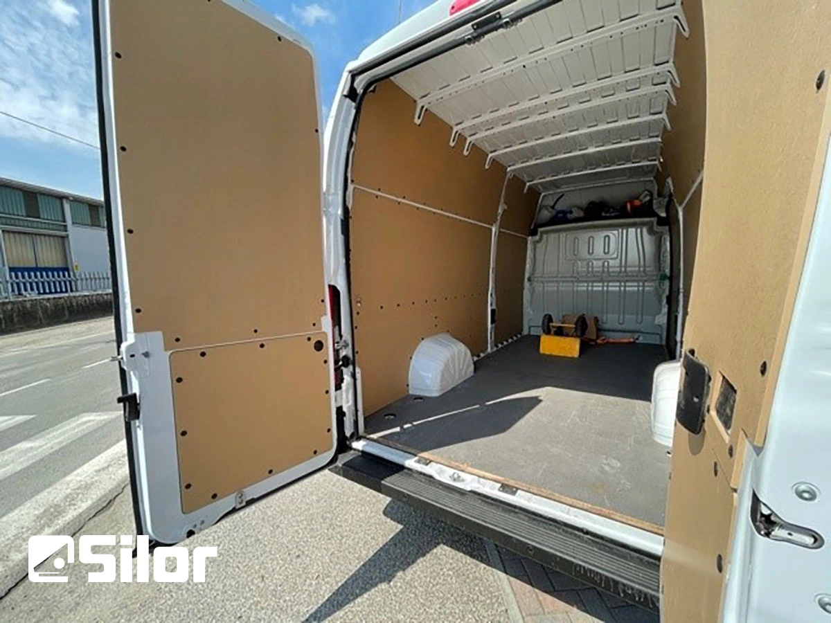 Interno di un furgone bianco foderato in legno chiaro.