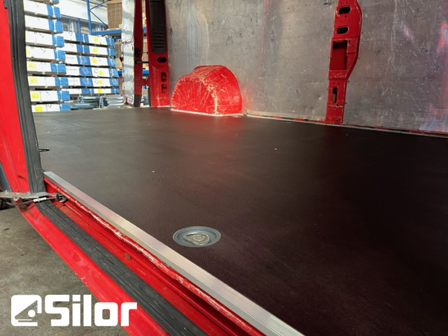 Interni di furgone con pavimento in legno scuro.