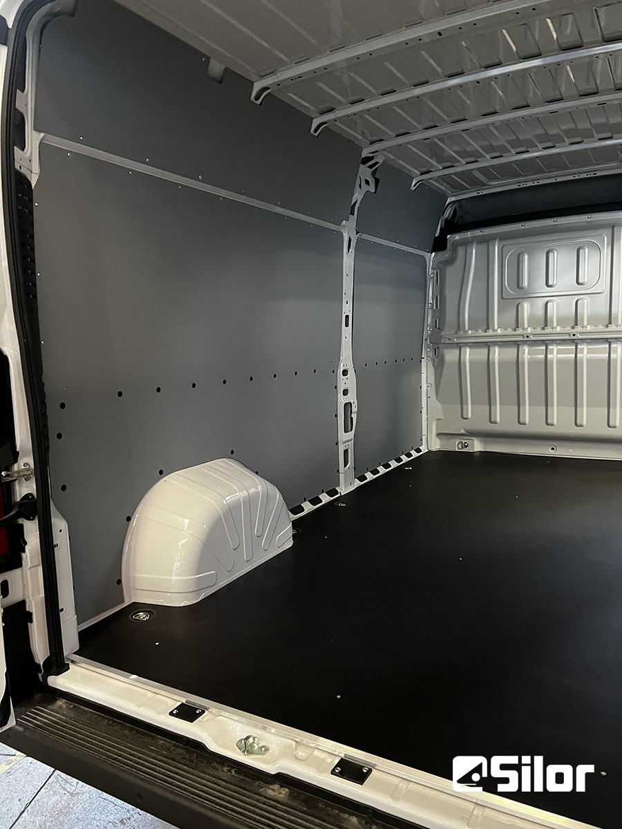 Interni di un furgone completamente rifiniti, pareti grigie e pavimento nero.