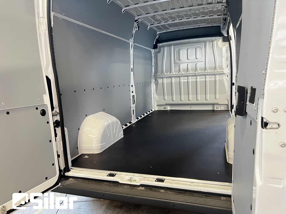 Interni di un furgone bianco vuoto con pavimento nero e pannelli grigi.