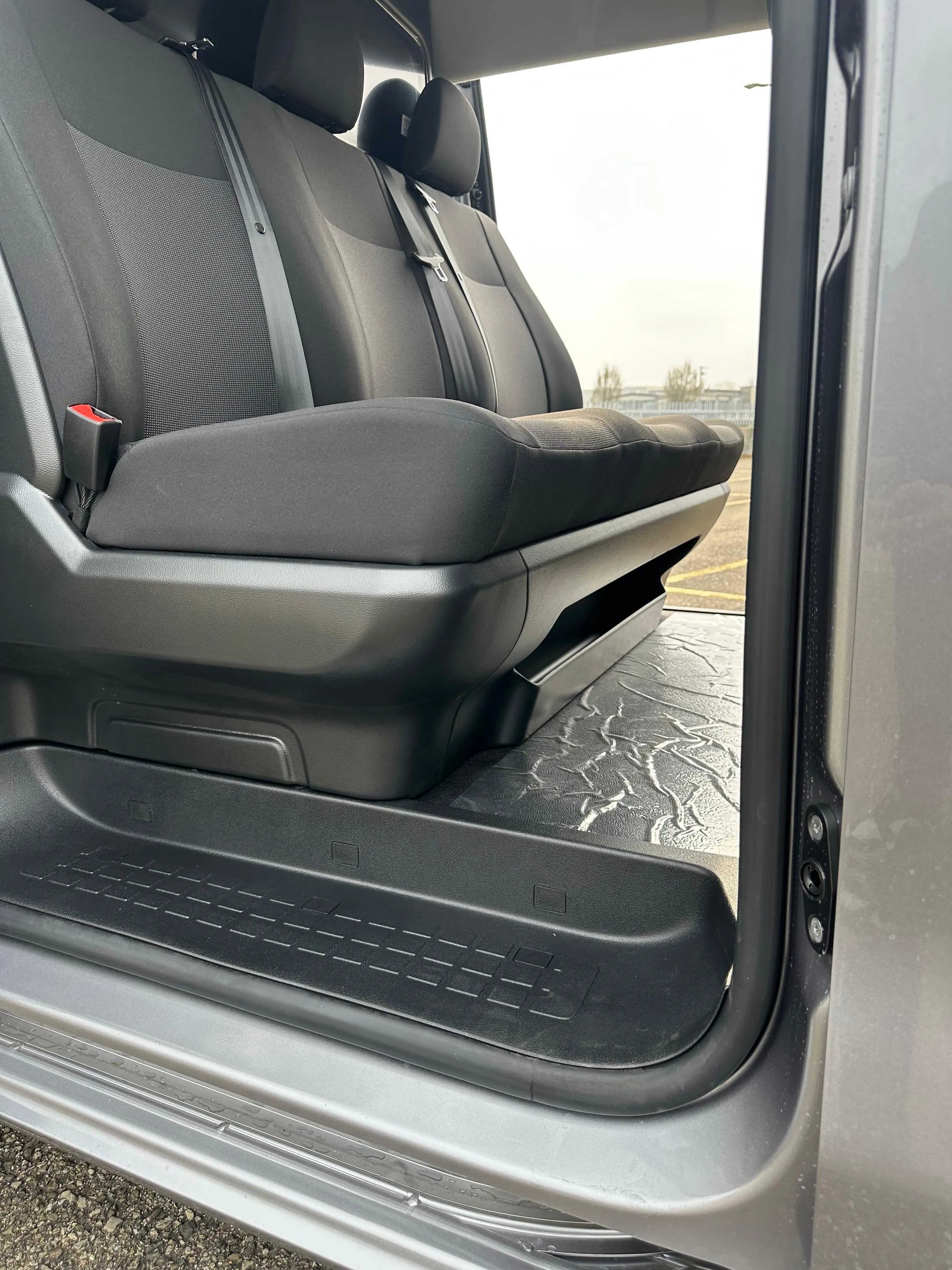 Interni di un'auto con sedili grigi e pedana.