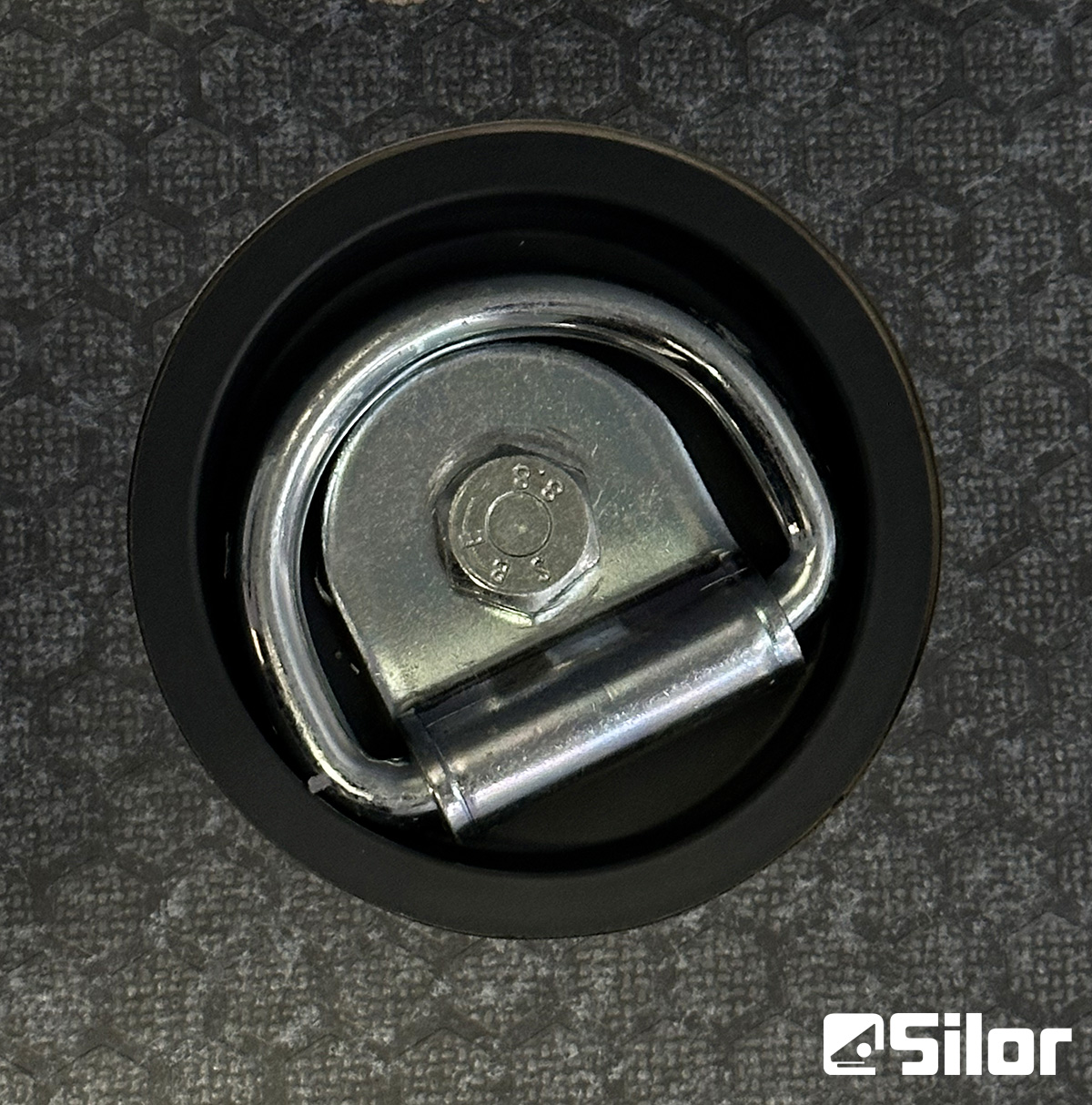 Un robusto punto di ancoraggio con anello a D in metallo fissato saldamente su una superficie resistente.