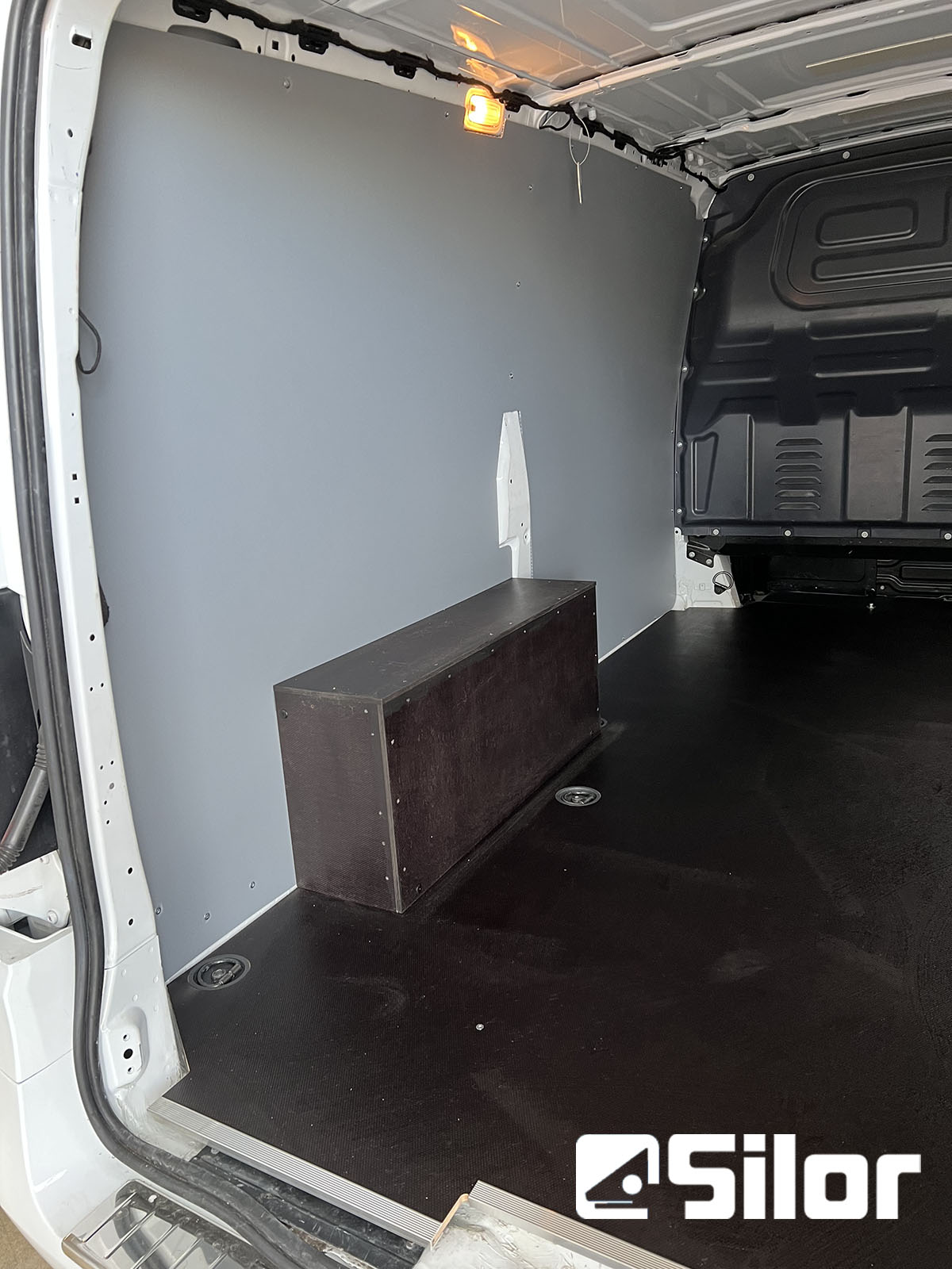 Interni di un furgone commerciale con pianale nero e parete grigia.