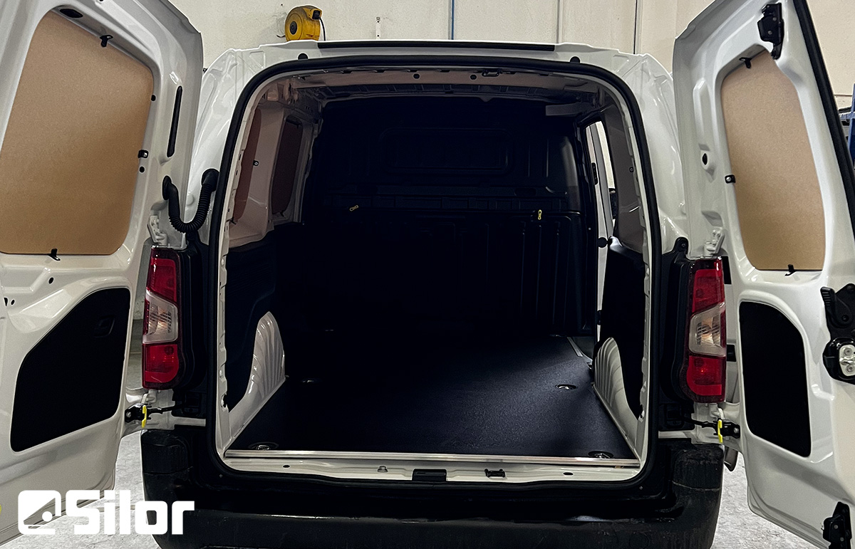 Un furgone bianco con le portiere posteriori aperte, che rivelano l'interno.