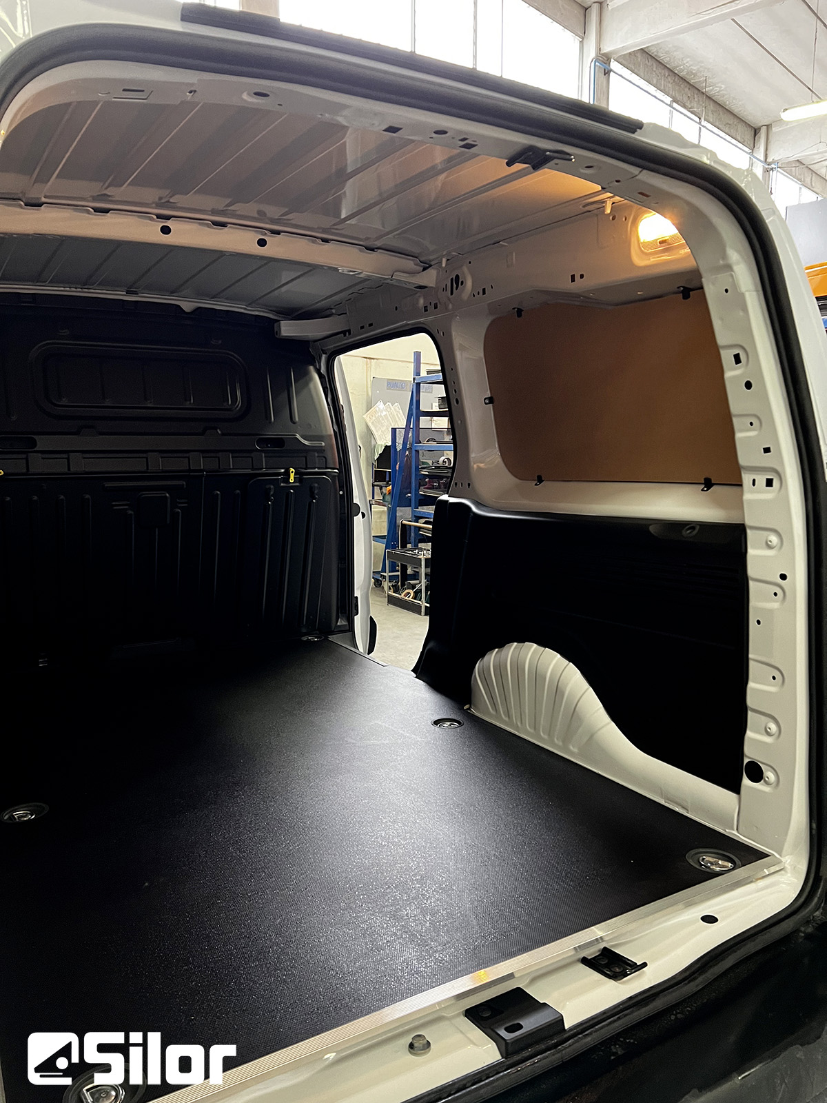 Interno di un furgone bianco con pianale nero.