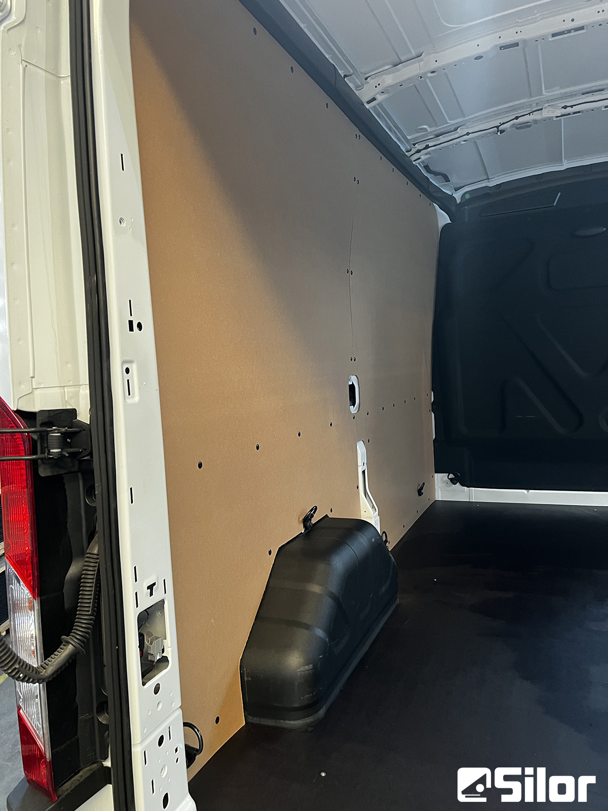 Interni di un furgone bianco con pannelli marroni e pavimento nero.