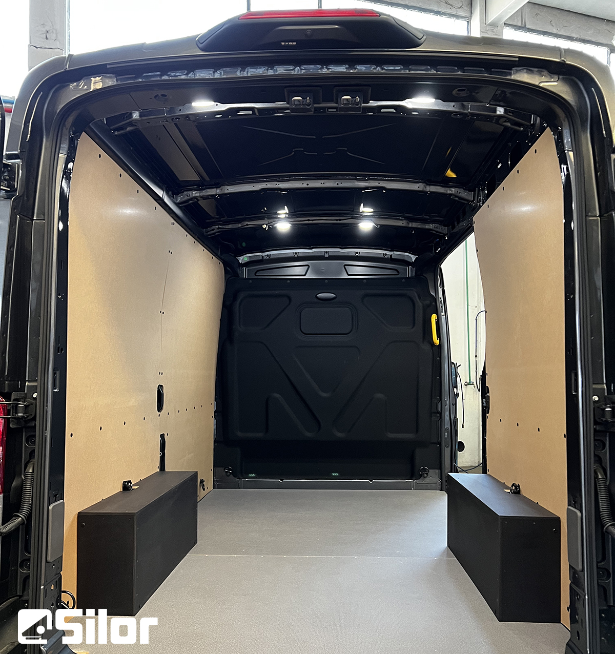 Interno di un furgone cargo nero con lati rivestiti in legno chiaro.