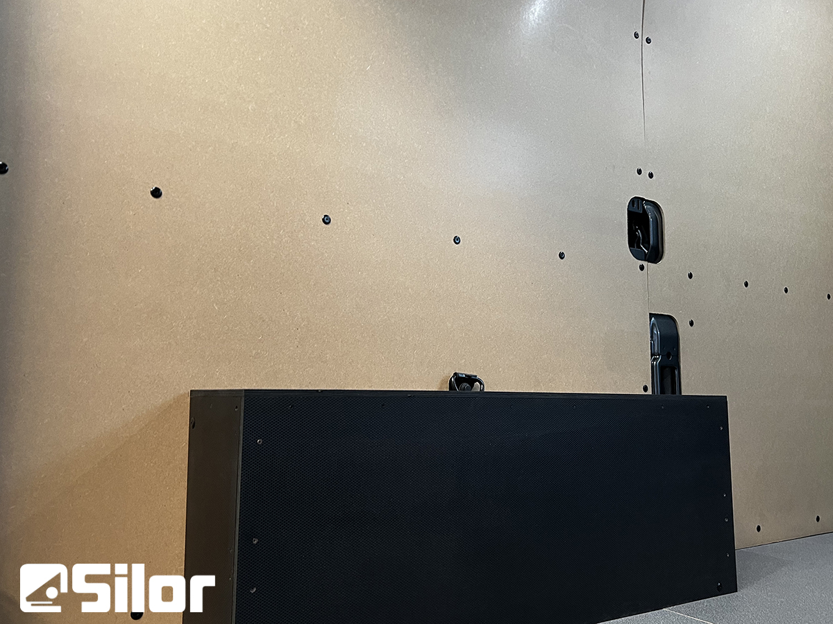 Interni di un furgone rivestito con pannelli in legno, con un mobile nero e il logo Silor.