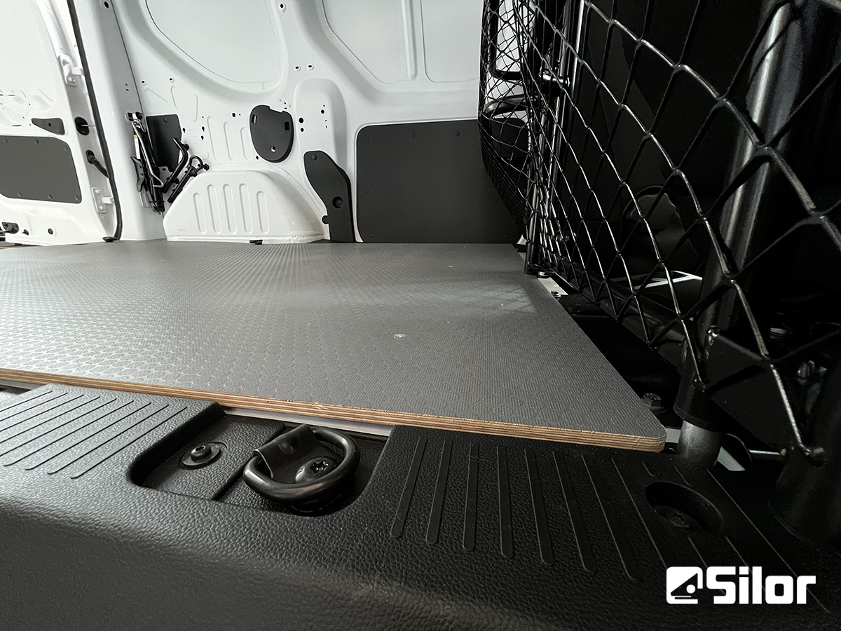 Interni di furgone bianco con pavimento grigio e divisorio in rete nera.