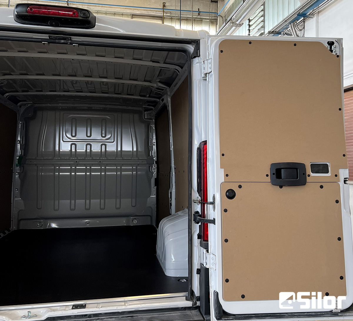 Interno di un furgone bianco con porte posteriori aperte e pannelli di legno.