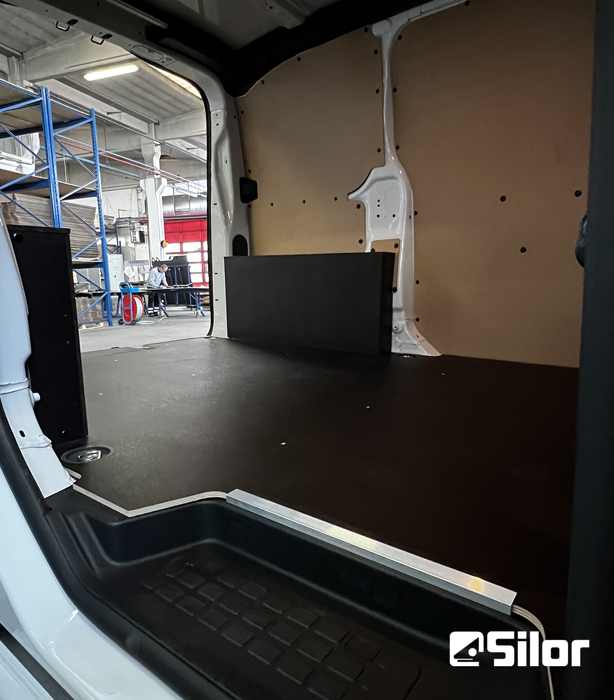 Interno di un furgone vuoto con pareti in legno e pavimento in gomma.