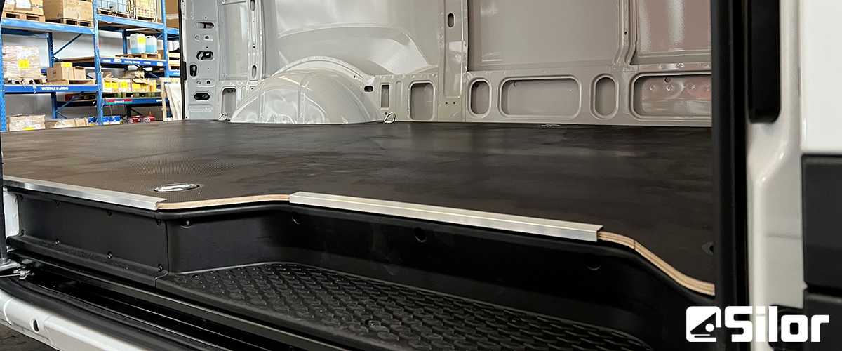 Interni di un furgone merci con pianale in legno.