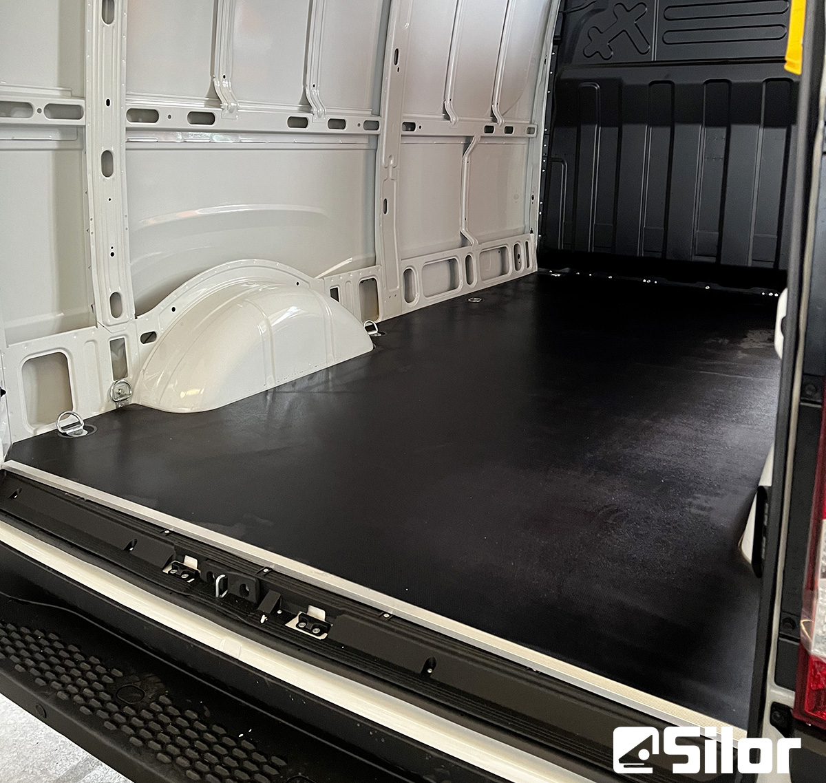 Interno di un furgone con pavimento nero.