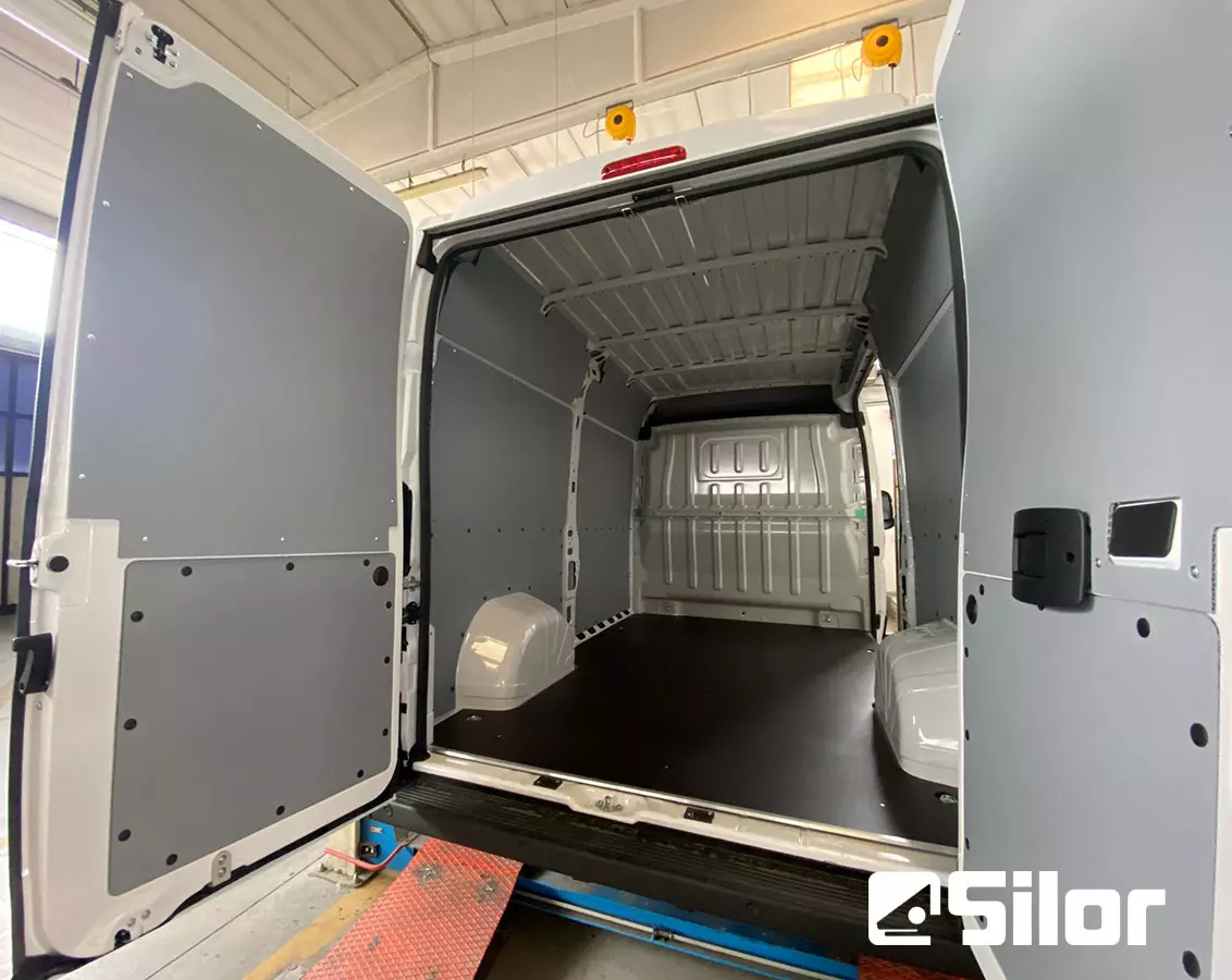 Interni di un furgone bianco con pannelli grigi e pavimento nero.