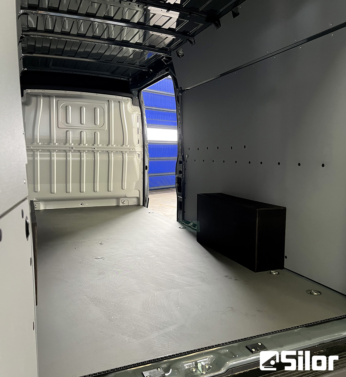 Interno di un furgone vuoto con rivestimento grigio e pavimento grigio.