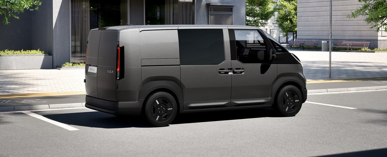 Furgone cargo elettrico Kia PBV grigio scuro parcheggiato in un ambiente urbano moderno.