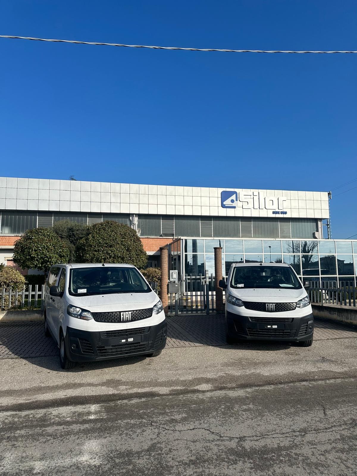 Due furgoni Fiat bianchi in sosta davanti alla sede Silor Sede Uno, sotto un cielo sereno.