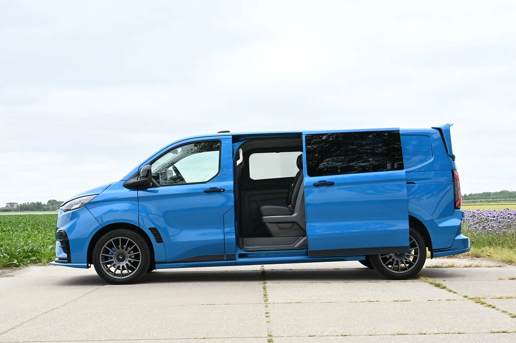 Furgone blu sportivo con porta scorrevole aperta, parcheggiato su strada di campagna.