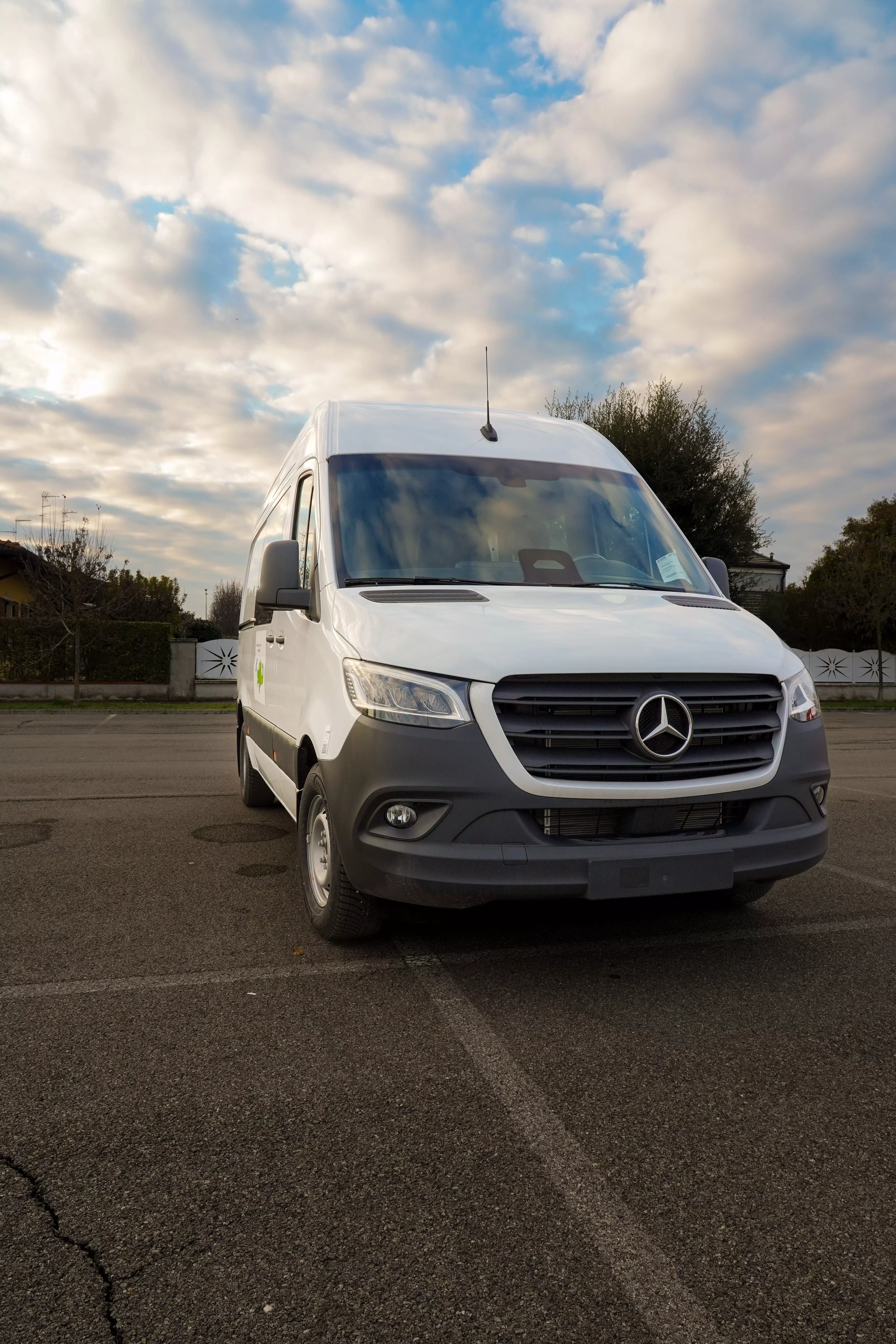 Mercedes Sprinter bianco in sosta, con un cielo parzialmente nuvoloso.