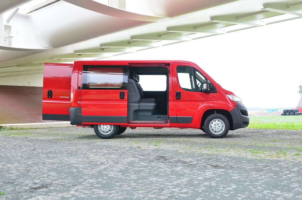 Un Citroën Jumper rosso brillante con porte aperte, parcheggiato sotto un viadotto.