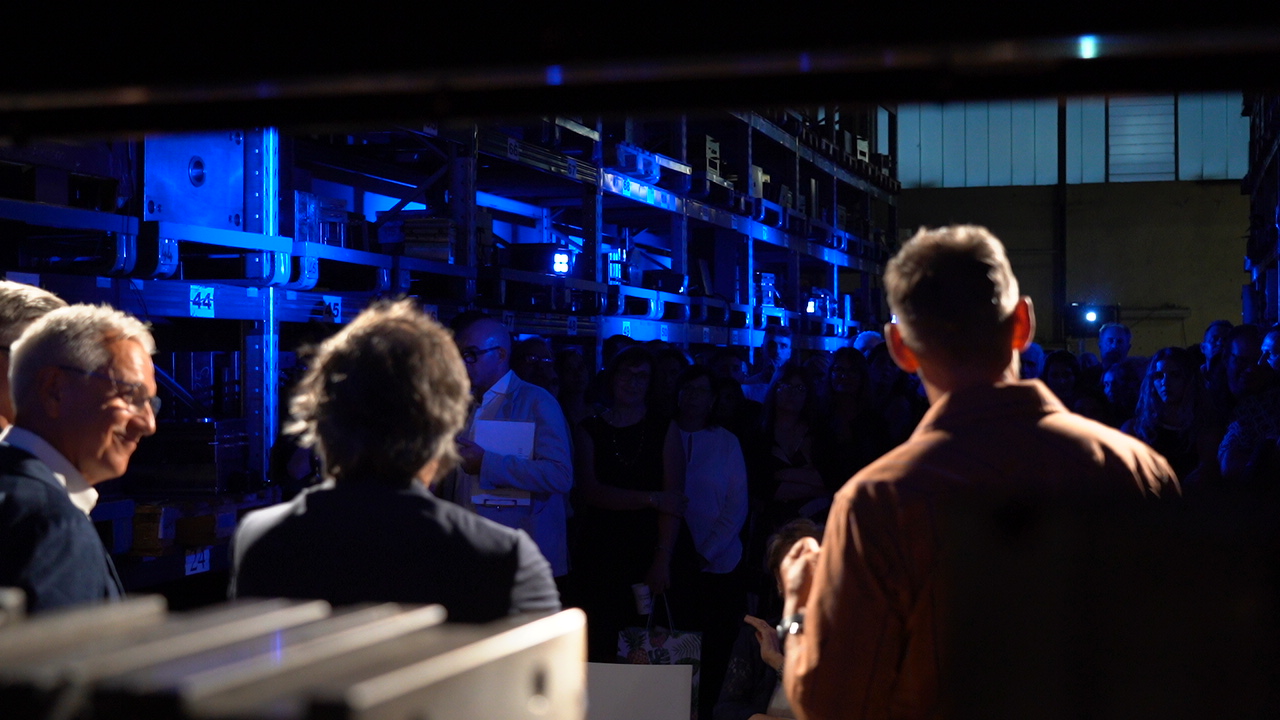 Un gruppo di persone si riunisce in una stanza buia con scaffali illuminati di blu.