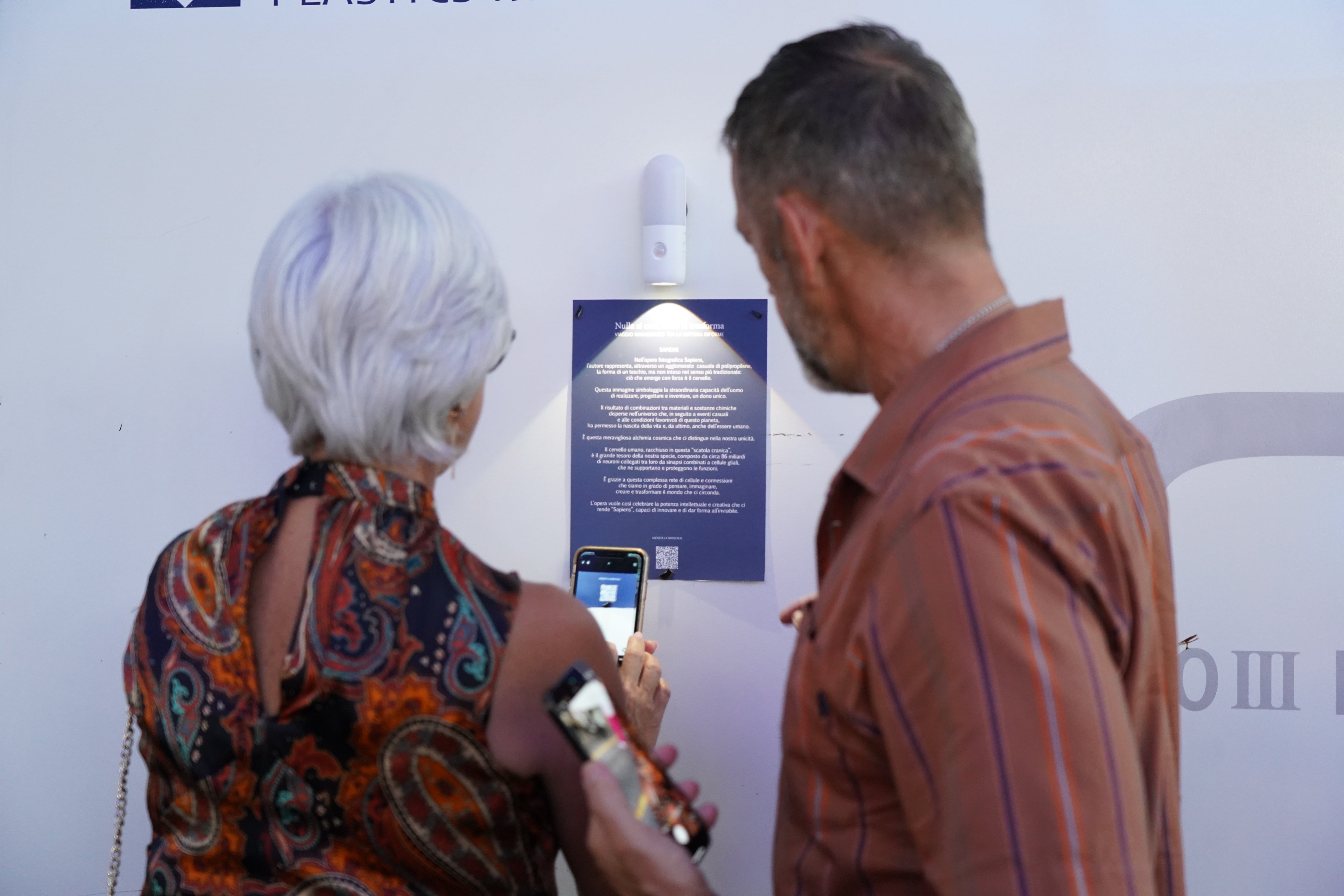 Visitatori che utilizzano i loro smartphone per scansionare un codice QR a una mostra d'arte.