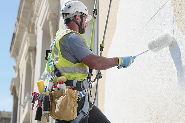 A painter on a lift painting the exterior of a large building.