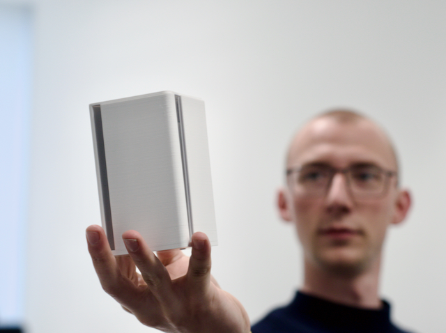 A person's hand gently cradling the IoT sensor, showcasing its palm-sized dimensions and lightweight construction, making it a convenient and portable solution for remote monitoring and data collection.
