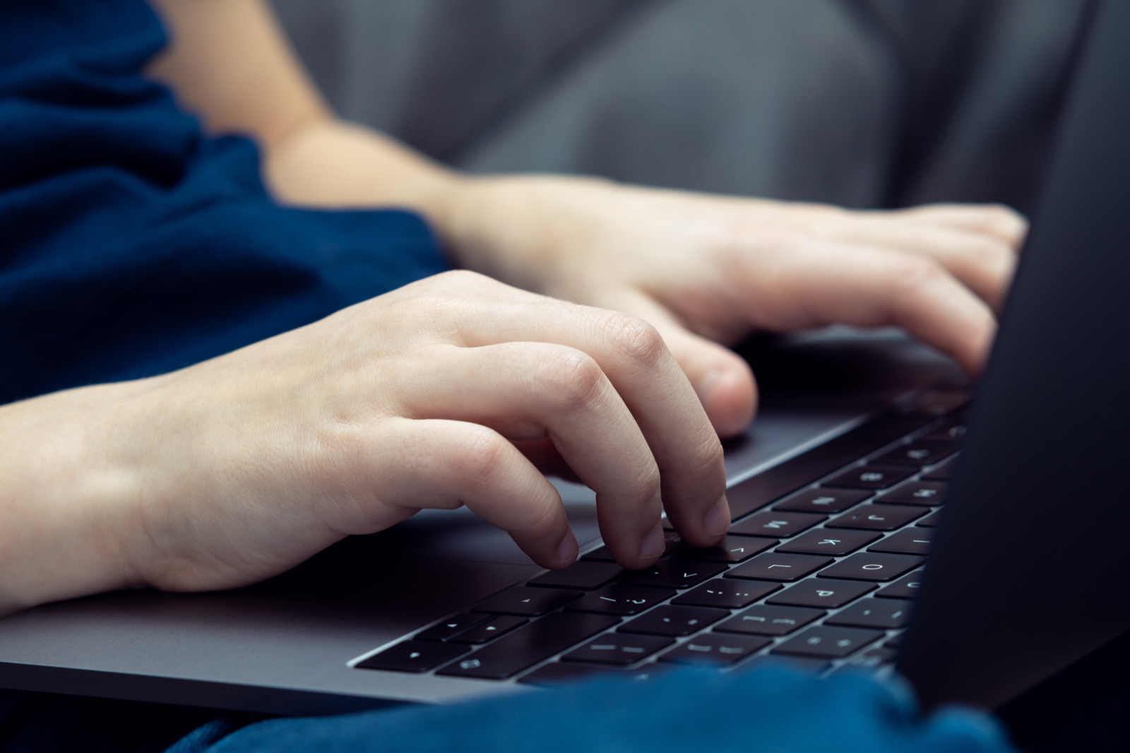 Unrecognizable person's hands typing on a laptop keyboard