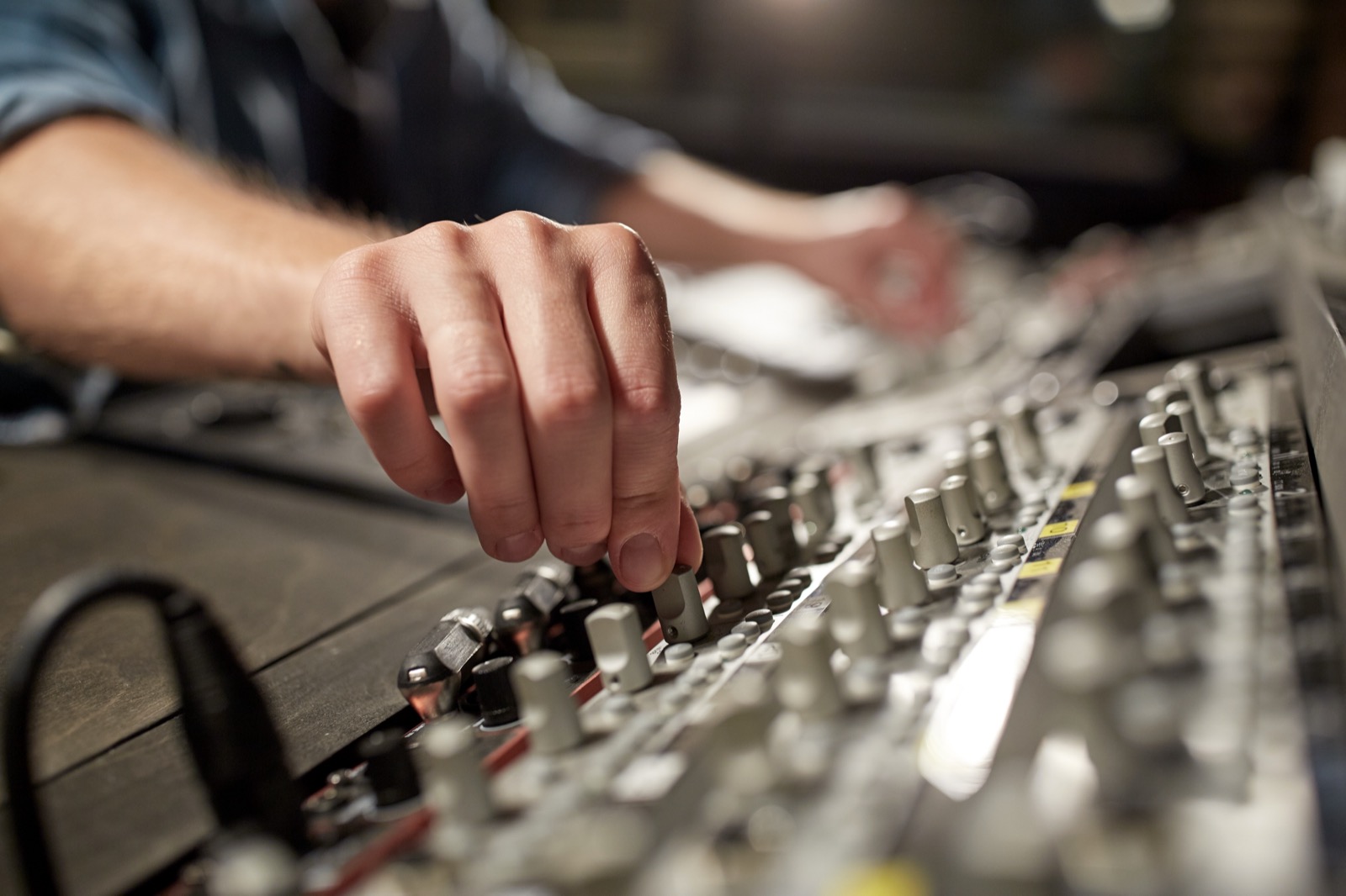 A hand adjusting EQ knobs on a mixing console