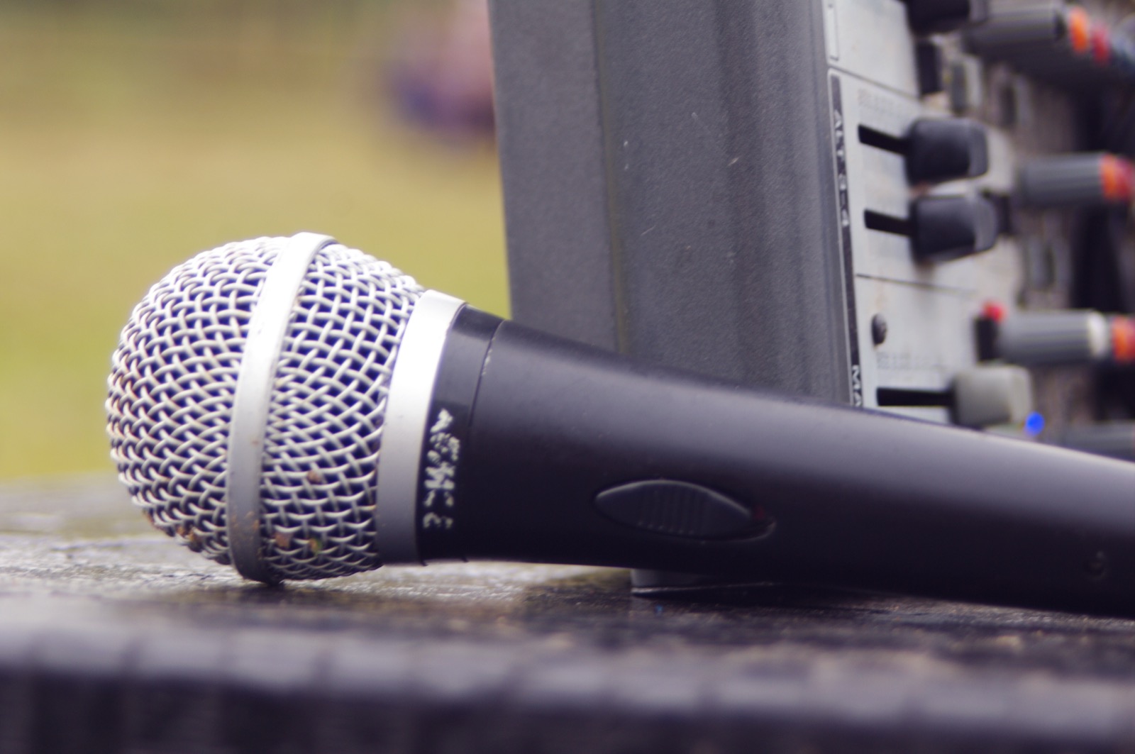 Close-up of a wireless microphone resting next to a mixing console
