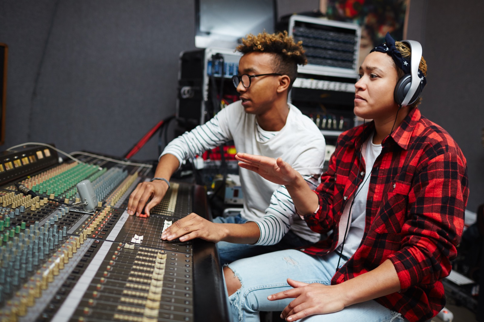 Two people working together at an audio mixing board