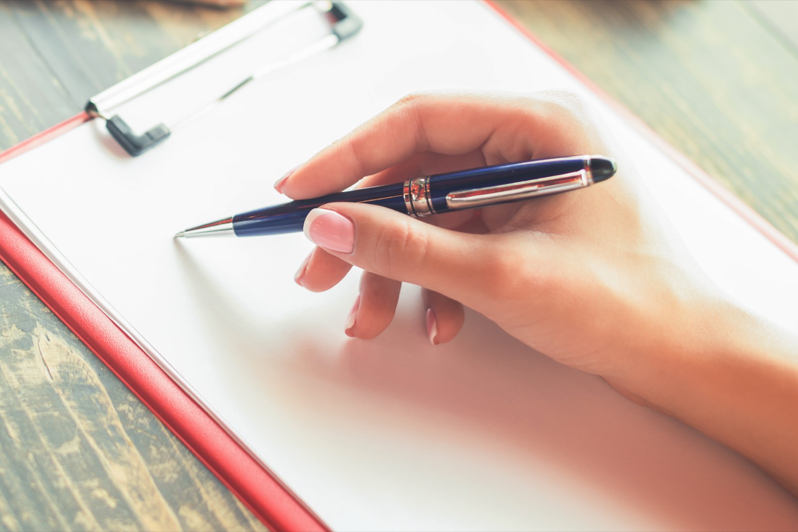 A hand holding a pen over a clipboard checklist