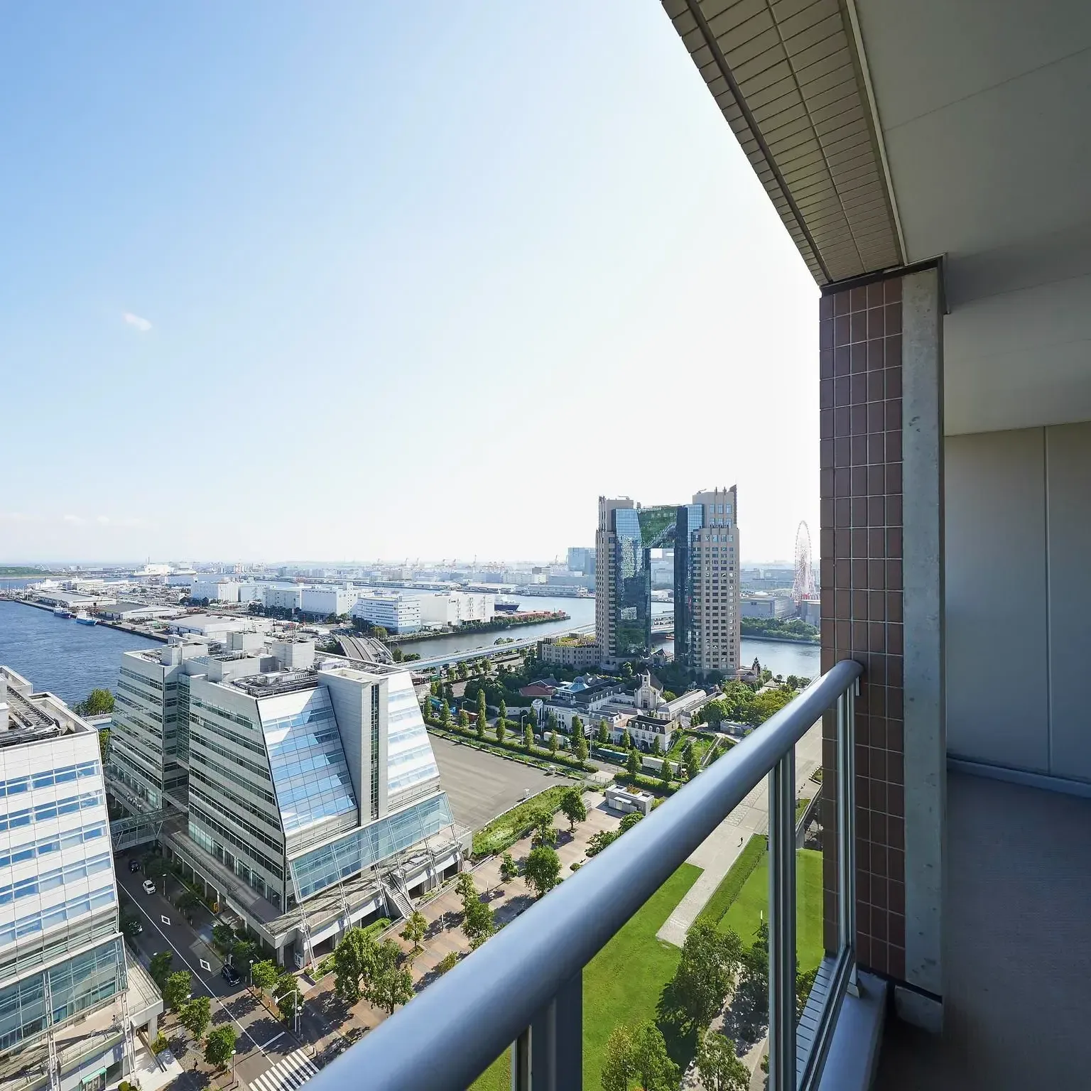 High-angle view of the Tokyo bay waterfront and Odaiba cityscape from a modern hotel balcony on a clear day.