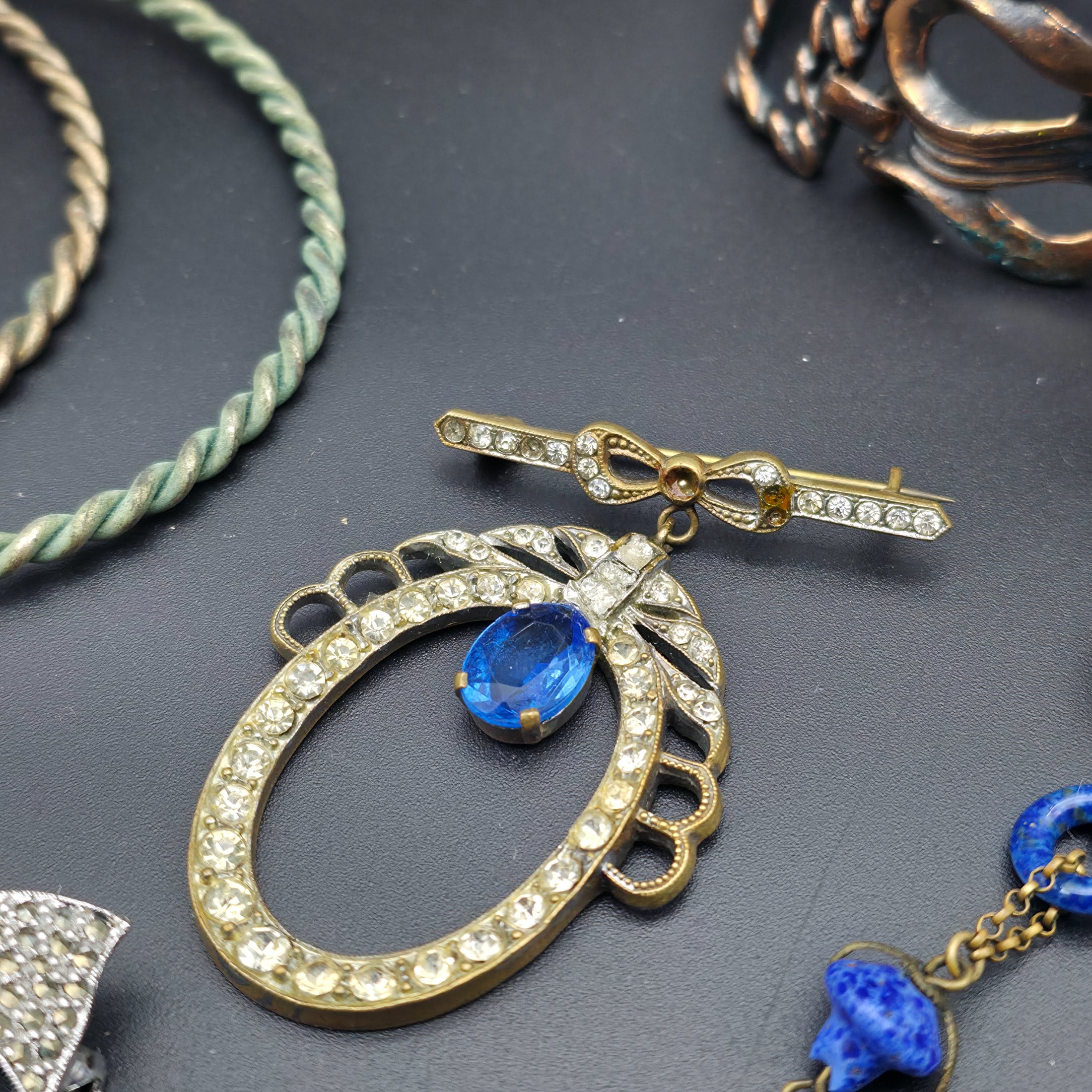 A diverse lot of vintage costume jewellery and decorative items from various eras, including necklaces, earrings, brooches, bracelets, a heart-shaped ceramic box, and a fabric pouch. - View 2