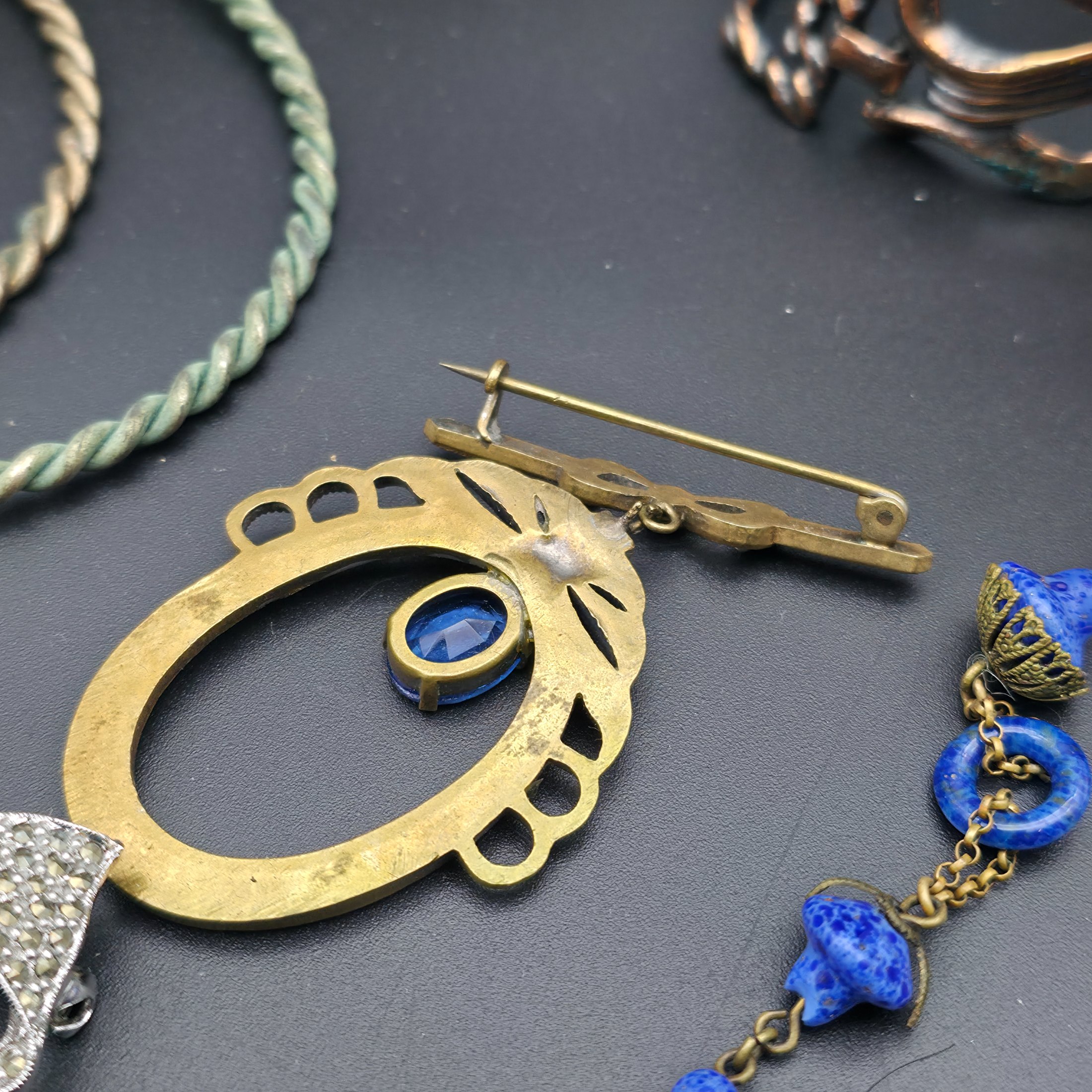 A diverse lot of vintage costume jewellery and decorative items from various eras, including necklaces, earrings, brooches, bracelets, a heart-shaped ceramic box, and a fabric pouch. - View 3