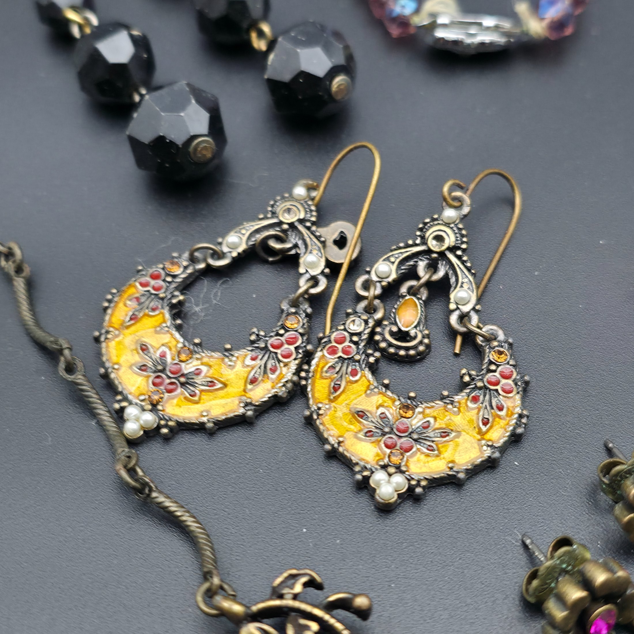A diverse lot of vintage costume jewellery and decorative items from various eras, including necklaces, earrings, brooches, bracelets, a heart-shaped ceramic box, and a fabric pouch. - View 4