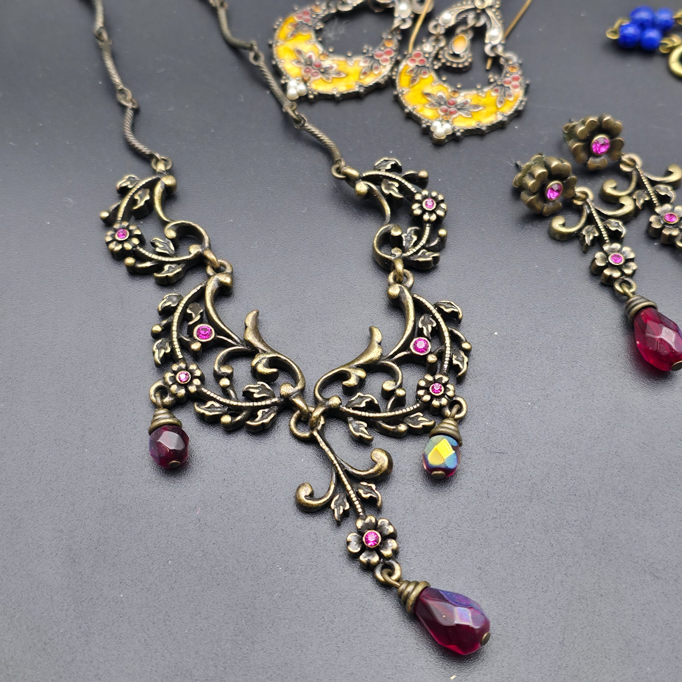 A diverse lot of vintage costume jewellery and decorative items from various eras, including necklaces, earrings, brooches, bracelets, a heart-shaped ceramic box, and a fabric pouch. - View 5