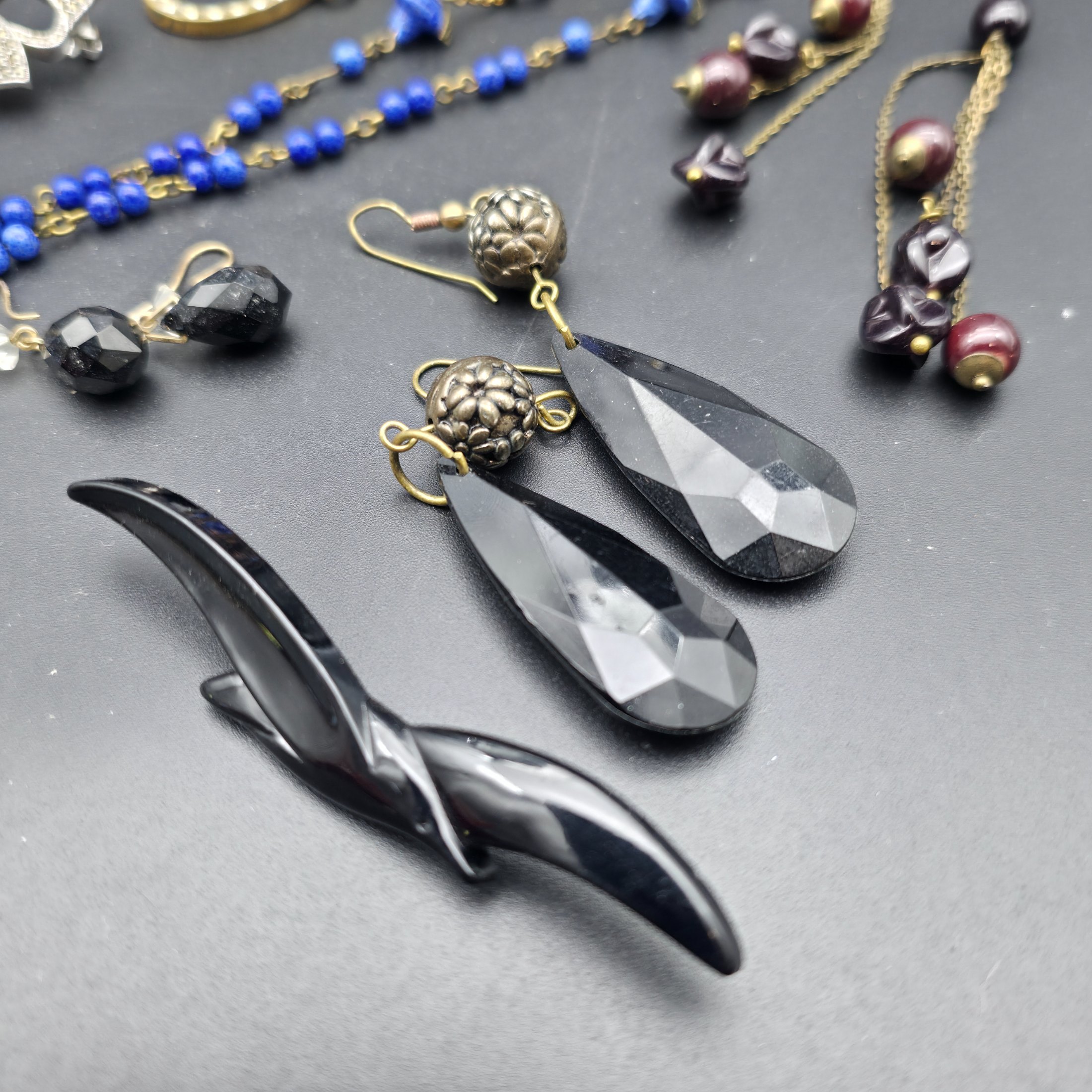 A diverse lot of vintage costume jewellery and decorative items from various eras, including necklaces, earrings, brooches, bracelets, a heart-shaped ceramic box, and a fabric pouch. - View 6