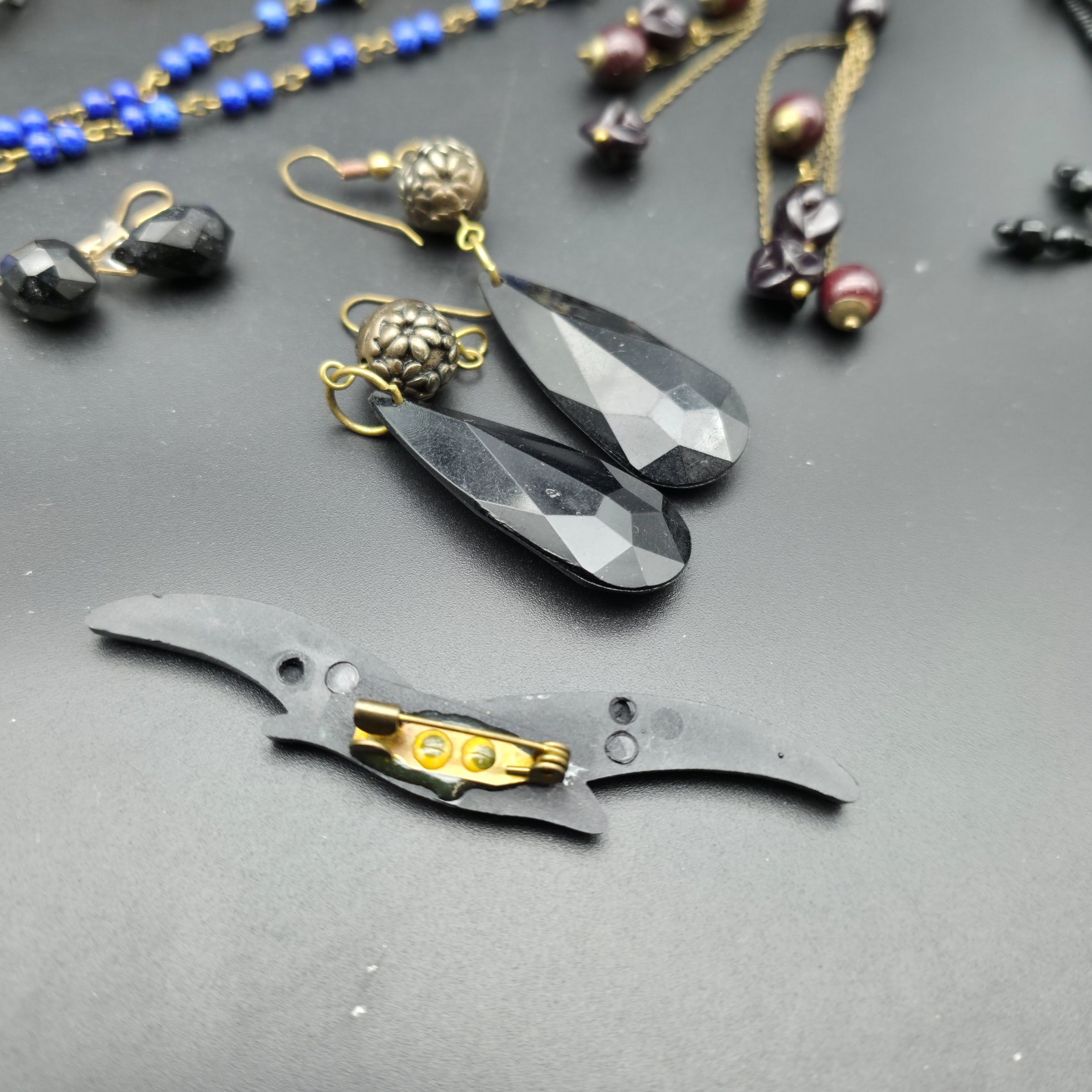 A diverse lot of vintage costume jewellery and decorative items from various eras, including necklaces, earrings, brooches, bracelets, a heart-shaped ceramic box, and a fabric pouch. - View 7