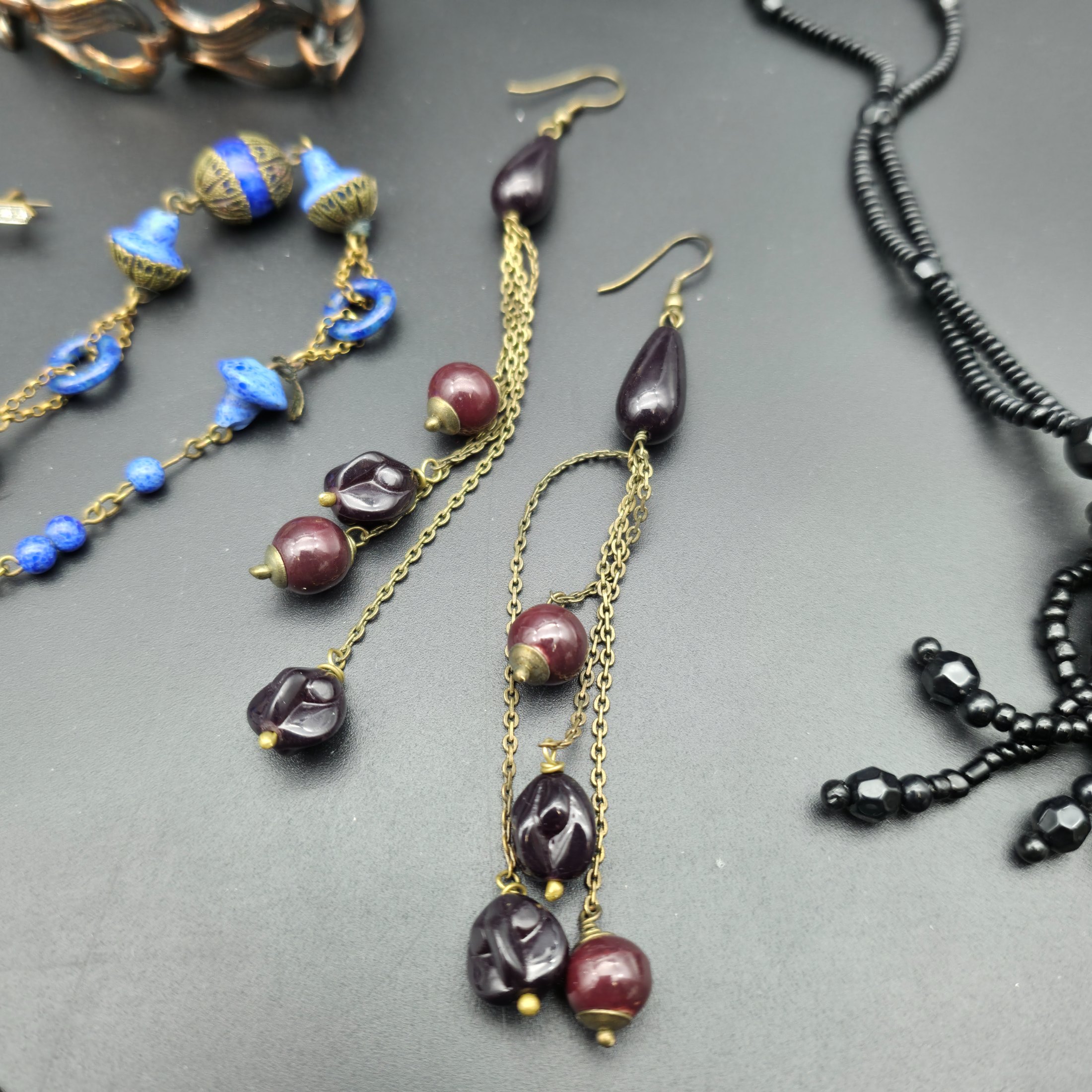 A diverse lot of vintage costume jewellery and decorative items from various eras, including necklaces, earrings, brooches, bracelets, a heart-shaped ceramic box, and a fabric pouch. - View 8