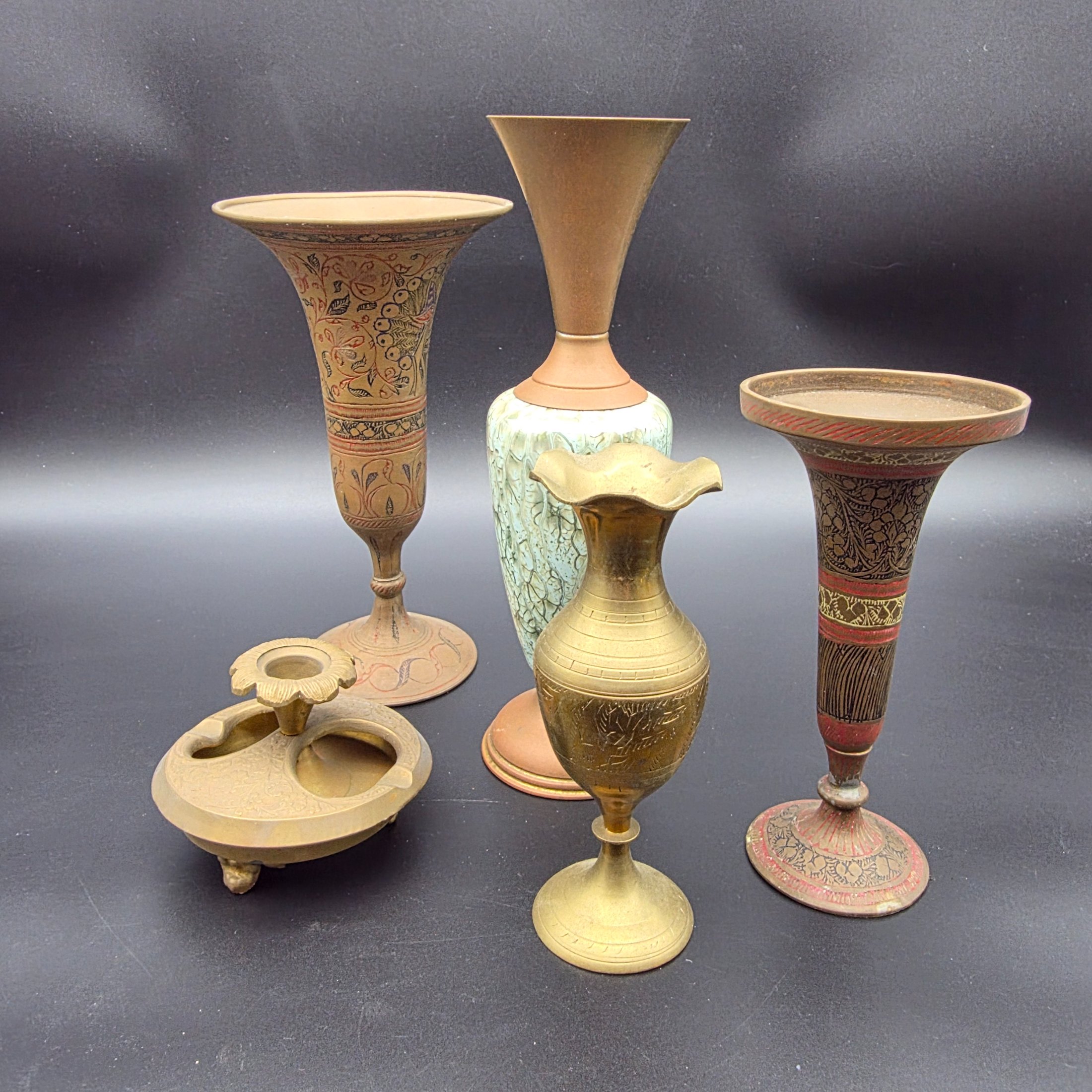 A curated collection of vintage decorative brass items, likely from the mid-20th century, featuring various engraved, enameled, and glazed finishes.