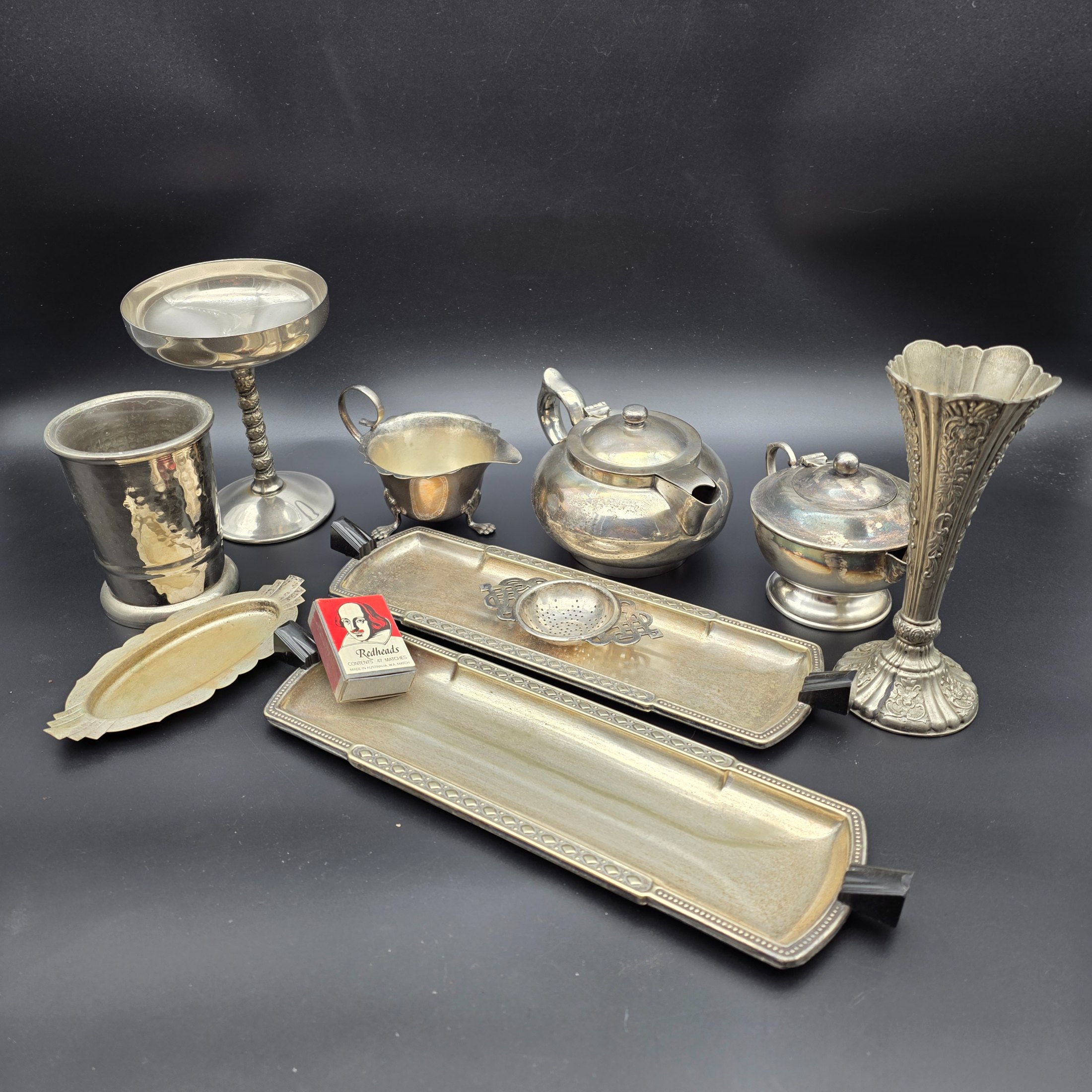 A varied collection of vintage F.B. Rogers silverplate items, including a compote, teapot, cream jug, sugar bowl, vase, goblet, and various trays, all showing signs of age and tarnishing.
