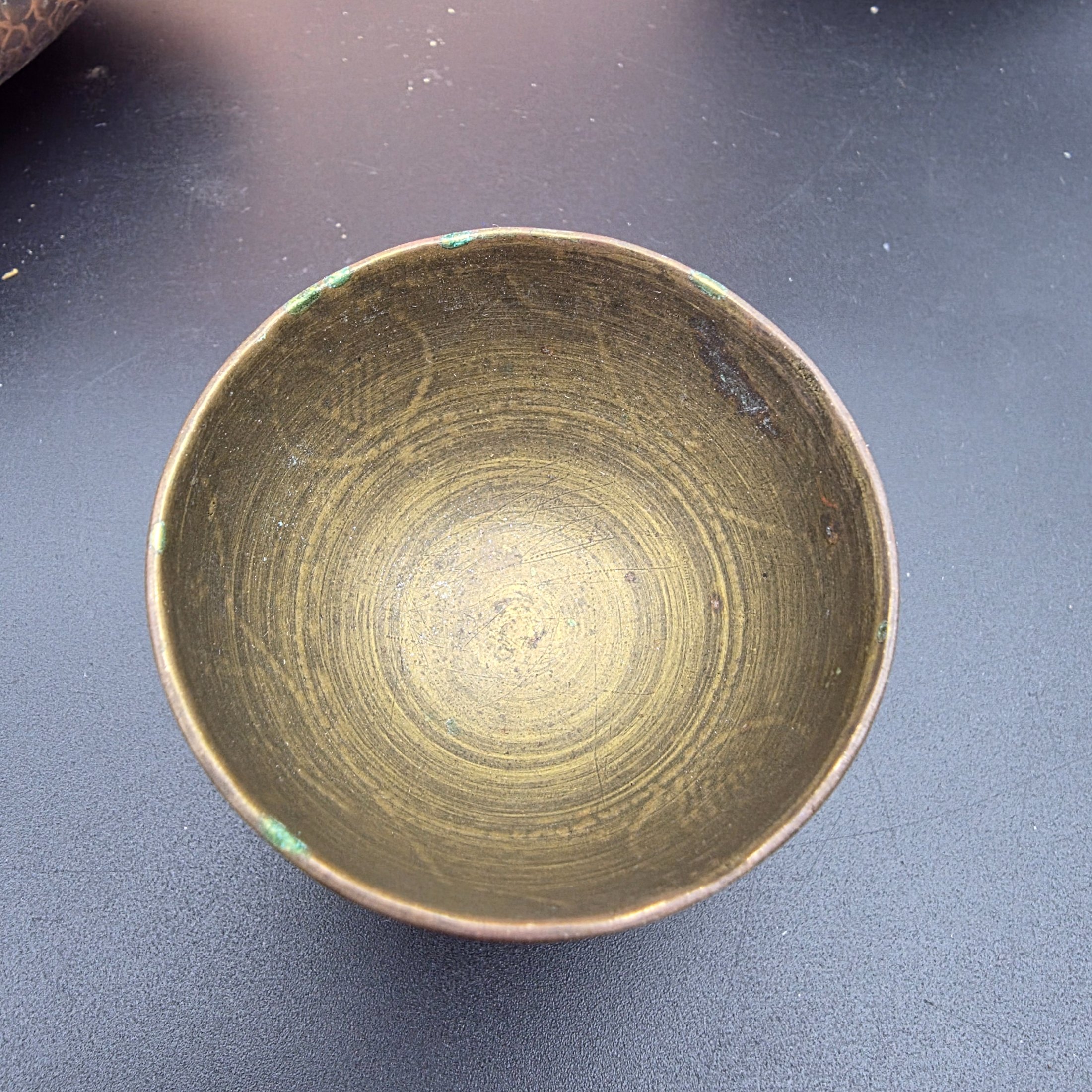 A diverse collection of vintage metalware, including a large copper wall plaque, a hammered copper dish, a small brass plate, two small brass cups, and a bronze/copper vase. - View 6